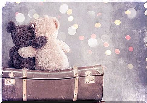 Teddy bears cuddling on top of a suitcase