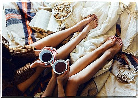 Girlfriends sitting in bed drinking coffee