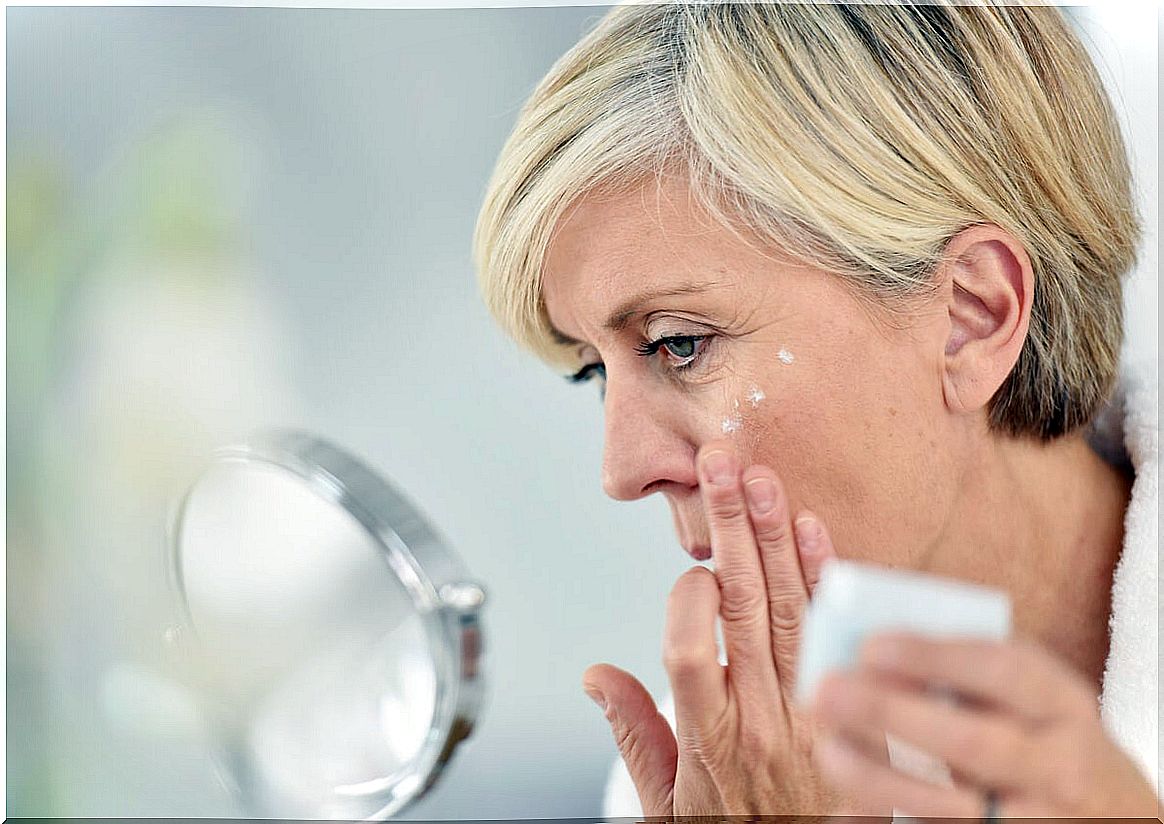 Middle-aged woman putting cream on her face