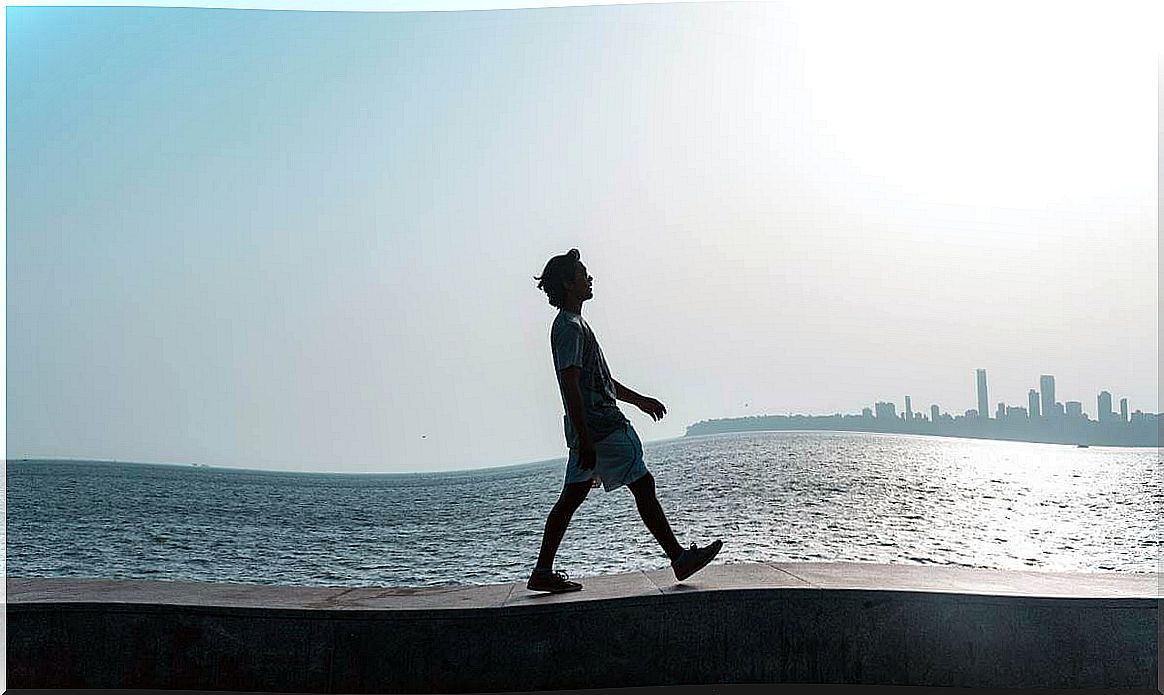 Boy walking along ledge before the sea thinking about improvising